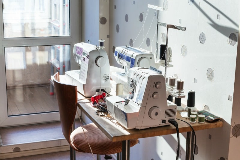 Workshop of seamstress at home - sewing machines and serger on table