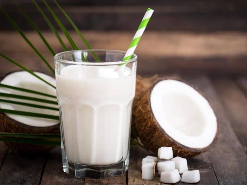 A glass of coconut milk and half of a coconut